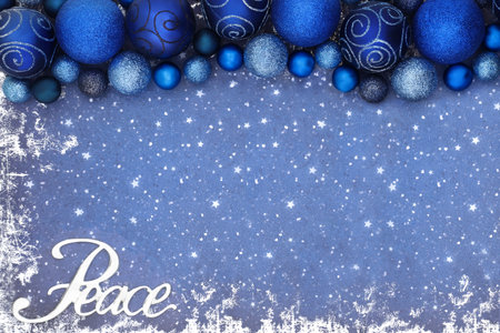 Christmas peace sign background border with blue sparkling glitter tree bauble decorations on grunge. Creative festive peace on earth concept for the Xmas holiday season.の写真素材