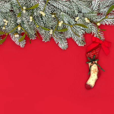 Christmas stocking for Xmas Eve snow fir background border on red with retro hanging metal tree decoration. Fun abstract wish believe concept for the holiday season.の写真素材
