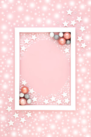 Pink Christmas background border with snow, stars, tree ball bauble decorations. Festive pastel design for holiday season and New Year with white frame.の写真素材