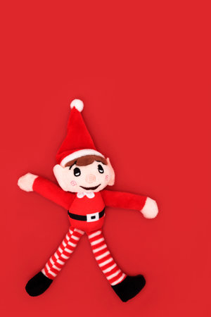 Christmas elf toy santa helper tree decoration. Minimal festive design symbol on red background for winter, Xmas Eve and New Year season.の写真素材