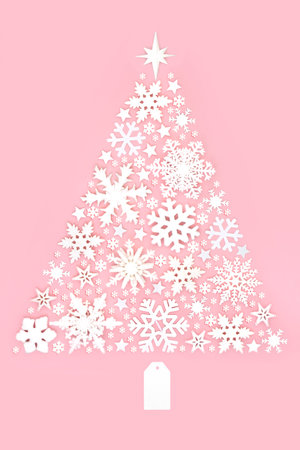 Christmas tree shaped decoration with snowflakes and stars on pastel pink background. Magical winter, new year symbol. Stylish composition for the holiday season.の写真素材