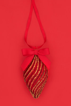 Christmas tree decoration in red and gold hanging from ribbon with bow. Traditional symbol for the festive Xmas holiday season.の写真素材