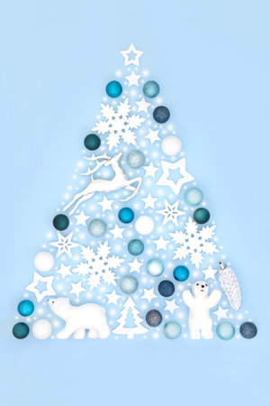 Abstract Christmas tree concept shape with of reindeer, snowflake, polar bear ornaments and Xmas symbols on pastel blue background. Festive surreal design for winter and Xmas season.の写真素材