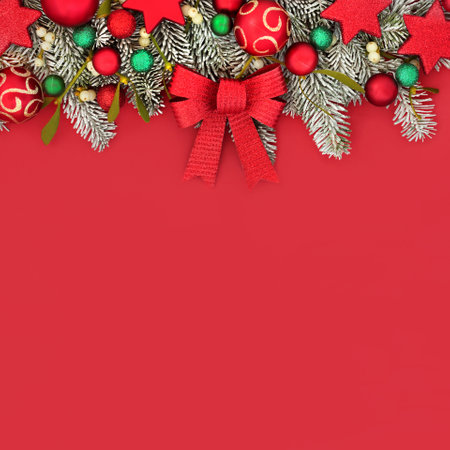Traditional Christmas festive fun red background border with tree decorations and winter fir mistletoe and snow. Composition for Xmas and New year holiday season.の写真素材