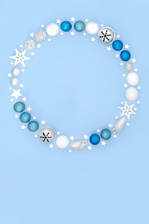 Magical Christmas wreath with tree bauble decorations on pastel blue background. Festive fantasy abstract concept for winter Xmas and New Year.の写真素材