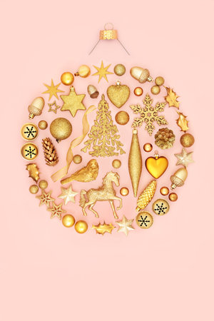 Christmas round shape tree bauble decoration concept with gold ornaments and symbols on pastel pink background. Festive abstract design for the holiday season. Flat lay.の写真素材