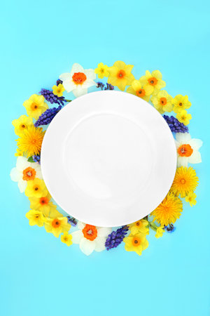 Easter and Spring abstract flower wreath arrangement surrounding white porcelain plate. Colourful fresh floral nature composition for Springtime and Mothers Day.の写真素材