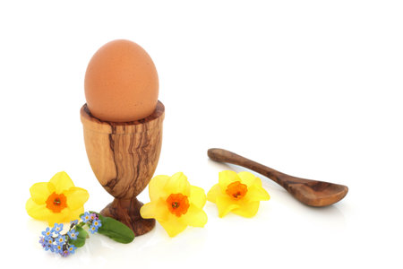 Healthy boiled egg in egg cup with narcissus flowers. Spring, Easter, beautiful nature, organic health food high in protein, omega 3 and vitamin D concept on white background.の写真素材