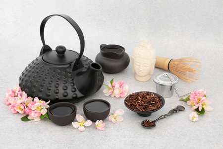 Kukicha twig and apple blossom tea drink. Japanese ceremony with ceramic teapot set, Buddha statue. Good health and inner peace, mindfulness concept. On mottled grey background.の写真素材