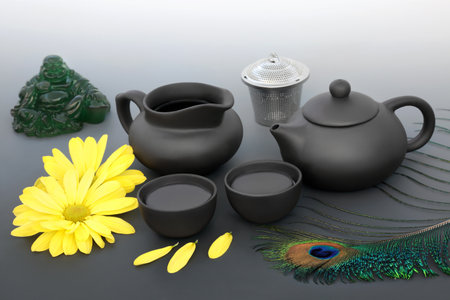 Traditional Japanese tea ceremony with chrysanthemum flowers, ceramic tea set, jade Buddha, peacock feather. Health drink high in potassium and magnesium. Mindfulness health concept. On gradient grey.の写真素材
