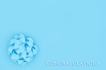 Congratulations design for birth of a male child with blue for a boy rosette bow on pastel background. Minimal creative gift composition.の写真素材