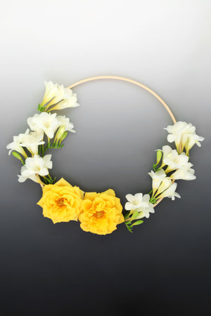 Summer wreath of freesia and rose flowers. Beautiful natural round wooden frame floral  layout on gradient grey background. Minimal nature concept. Top view, flat lay.の写真素材