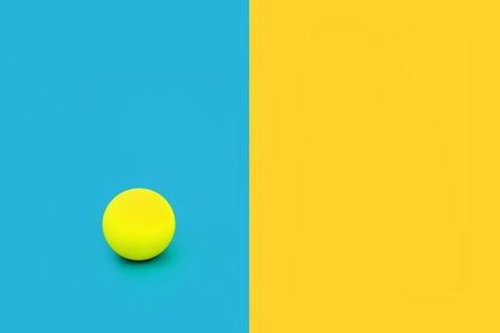 Dare to be different and independent concept with vivid blue and yellow contrast background with ball. Minimal solitary, alone, leadership, stand out in a crowd composition. Flat lay, copy space.の写真素材