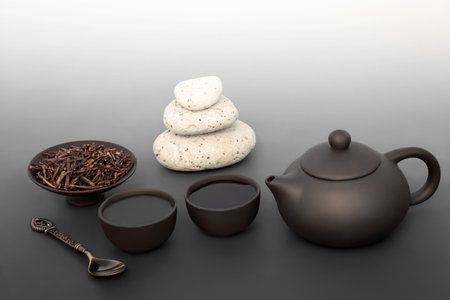 Japanese kuchika tea ceremony for balance with pebble stack, ceramic tea set. Zen spiritual mindfulness harmony concept on gradient grey. Healthy asian culture drink.の写真素材
