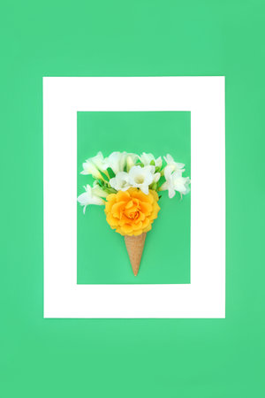 Ice cream waffle cone surreal summer flower concept with rose and freesia flowers, frame on green background. Abstract minimal trendy fun floral nature composition for summertime.の写真素材