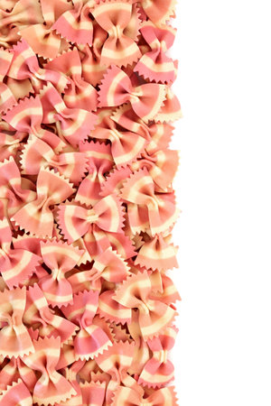Italian farfalle bow tie pasta on white background. Beetroot food dye used for pink colour. Healthy gourmet eating concept. Flat lay top view, copy space.の写真素材