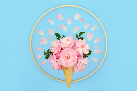 Surreal pink rose flower ice cream cone on pastel blue background with loose petals and round wooden frame. Minimal summer creative art fun food nature concept.の写真素材