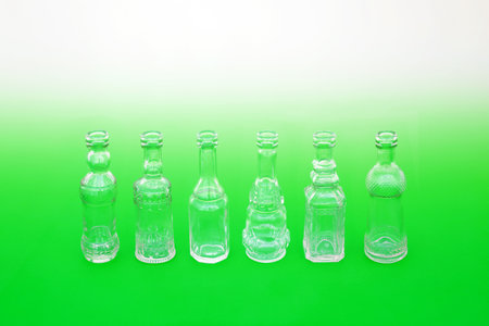 Go green use recycled glass bottles not plastic concept with line of old retro glass bottles on gradient green white background. Save the planet, sustainable abstract composition.の写真素材