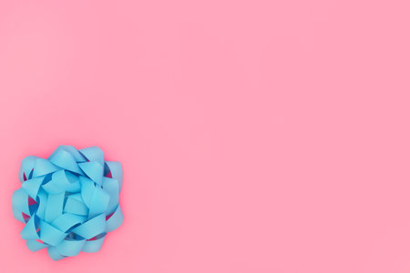 Blue rosette bow on contrast pink background. Minimal design composition for birthday or birth of a baby boy child. Flat lay. Copy space.の写真素材