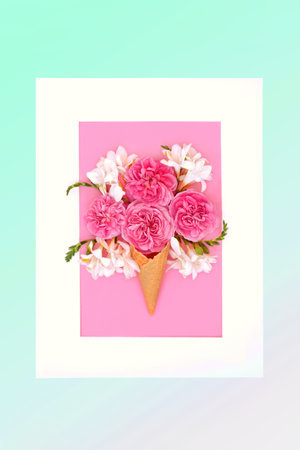 Summer fun ice cream cone with rose and  freesia flowers, white frame on gradient pastel green background. Trendy surreal nature food gift concept.の写真素材