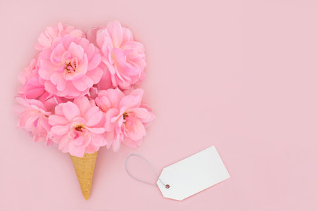 Surreal rose flower abstract ice cream waffle cone with gift tag. Minimal design on pastel pink background. Summer creative fun concept for birthday anniversary Valentines Wedding or Mothers Day.の写真素材