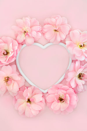 Summer rose flower abstract heart shape frame composition on pastel pink background. Creative floral nature concept for Valentines Day, Mothers Day, wedding, anniversary or birthday.の写真素材