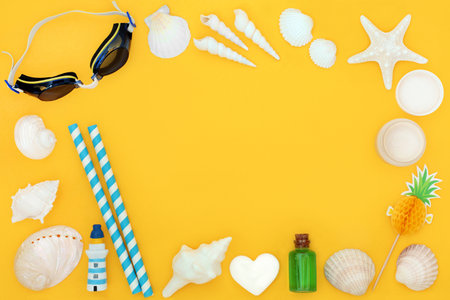 Beach accessories and symbols of summer with protective swimming goggles, moisturizer and seashells. Travel holiday fun in the sun vacation concept on yellow background.の写真素材