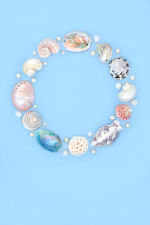 Seashell and oyster pearl wreath decoration. Summer garland with collection of assorted shells and pearls on blue background. Circular natural nature design, beach and seaside art.の写真素材