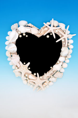 Heart shape seashell and oyster pearl wooden frame on gradient blue and white background with chalkboard. Abstract summer sea life nature border.の写真素材