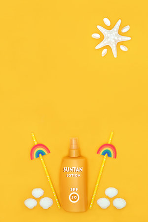 Factor fifty suntan lotion bottle for summer holiday natural skincare protection with rainbow straws, decorative shells, abstract starfish sun on yellow.の写真素材