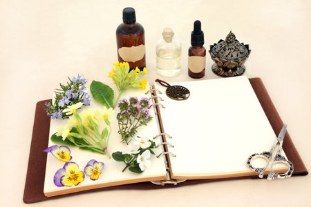 Naturopathic herbal medicine preparation with flowers, herbs and essential oil bottles with notebook. Natural spring floral nature concept for flower essences and remedies on hemp paper.の写真素材