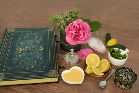 Love potion preparation for magic spell with ingredients of rose flower, quartz crystal, thyme, mint, lemon fruit and honey with old book of spells. Occult magical concoction.の写真素材