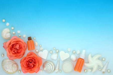 Rose flower beauty treatment with exfoliation salts, shower gel, soap and decorative seashells and pearls on gradient blue. Plant based natural pure anti aging skincare.の写真素材