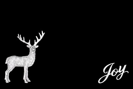 Christmas Eve silver reindeer tree ornament with Joy sign on black background. Festive symbol santa helper design for greeting card, gift tag, label.の写真素材