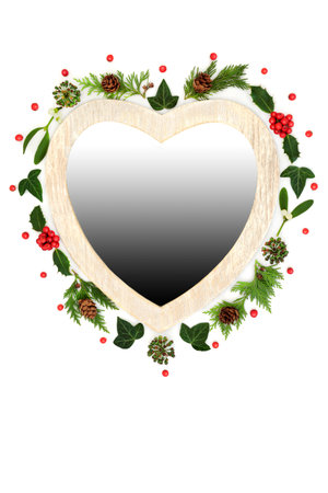 Christmas heart shape wreath with holly, mistletoe and festive winter greenery. Traditional symbol for the festive season on white background with gradient gray fill.の写真素材