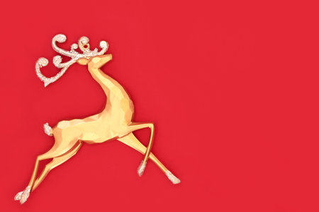 Christmas eve gold reindeer ornament on red background. Merry Christmas Noel Yule greeting card, gift tag, letter, menu, invitation.の写真素材