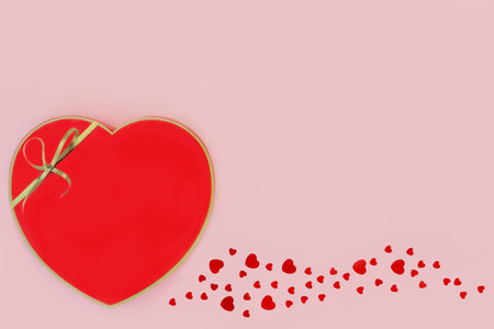 Red chocolate heart shaped gift box and decorative confetti hearts on pink background. Valentines day, birthday,  Mothers Day, anniversary design.の写真素材