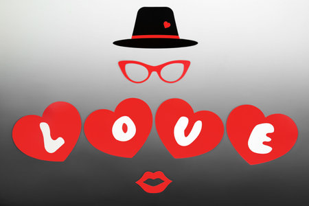 Valentines Day love abstract design with letters on red heart shapes, with luscious lips, glasses and black hat. Surreal valentine romance concept on gradient gray white.の写真素材
