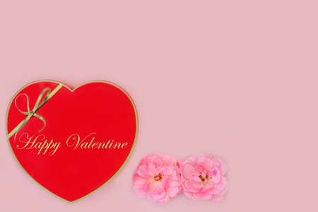 Happy Valentine heart shaped chocolate gift box and rose flowers on pink background. Valentines day beautiful love floral feminine arrangement.の写真素材