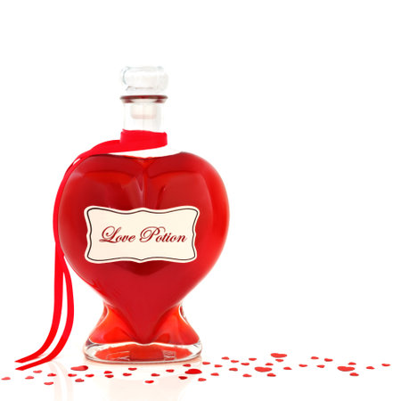 Heart shaped love potion bottle with elixir and loose red confetti heart decorations on white background. Valentines Day abstract concept with liquid magic  concoction.の写真素材