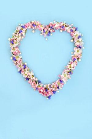 Heart shaped wreath with bluebell, apple blossom flowers and pearls for Spring and Beltane. Abstract floral design for birthday Mothers Day card, logo, gift tag or invitation on blue.の写真素材