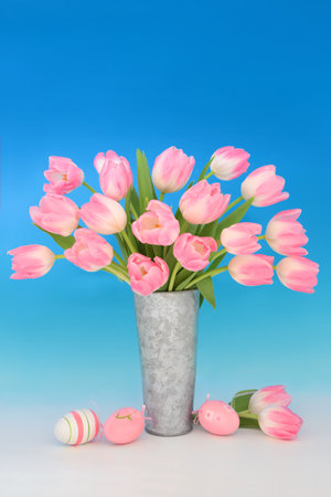 Spring tulip flower arrangement and pink easter eggs on gradient blue white background. Floral nature fun food design for the holiday season.の写真素材