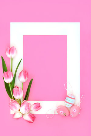 Happy Easter background with  tulips flowers and decorated eggs with white frame on pink. Spring and Eastertime minimal floral nature fun design on pastel pink background.の写真素材