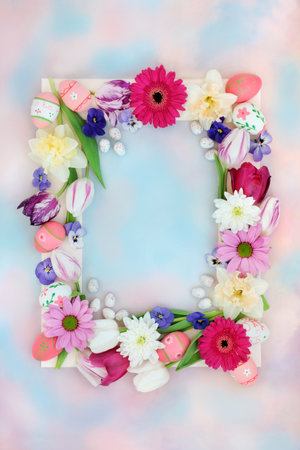 Decorative Easter background border with eggs, flowers on pastel blue pink sky cloud background. Natural nature frame design for the holiday and Spring season.の写真素材