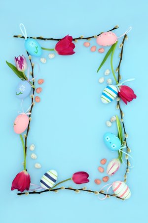 Easter background border with edible and decorative eggs, flowers and willow branch on pastel blue. Natural nature frame design for the holiday season. Flat lay.の写真素材