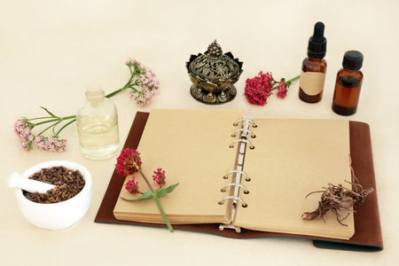 Valerian herb root with flowers, notebook and essential oil bottles. Used in herbal medicine to treat insomnia, is a sedative and tranquilizing natural adaptogen drug.の写真素材