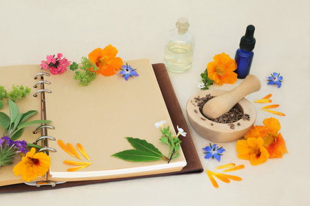 Flowers and herbs for naturopathic, medicinal and aromatherapy treatments. Herbal medicine ingredients for alternative remedies with recipe notebook on hemp paper background.の写真素材