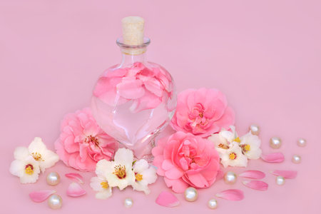 Rose and orange blossom flower perfume in heart shaped bottle on pink with loose flowers and pearls. Floral beauty product, gift for Valentines Day, birthday, anniversary or Mothers day.の写真素材