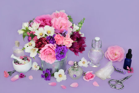 Preparation of flowers and herbs for aromatherapy and naturopathic herbal medicine. Essential oil bottles with quartz crystal for alternative remedies on lilac background.の写真素材