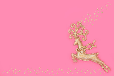 Christmas Eve gold reindeer tree bauble ornament on pink background with gold sparkle decorations. Magical fantasy symbol for Xmas Yule. Copy space.の写真素材